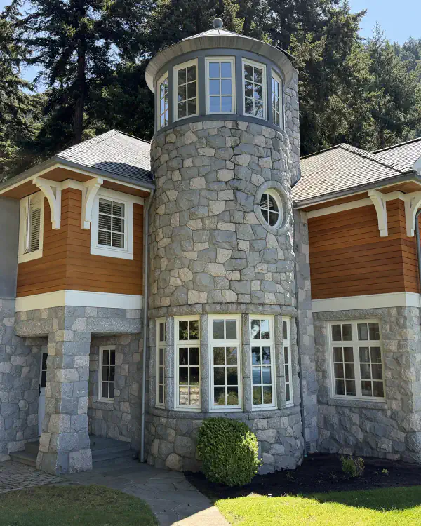 A stone house with a round tower, its many windows clean and bright.