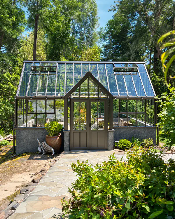 A glass greenhouse with clear panes in a garden.