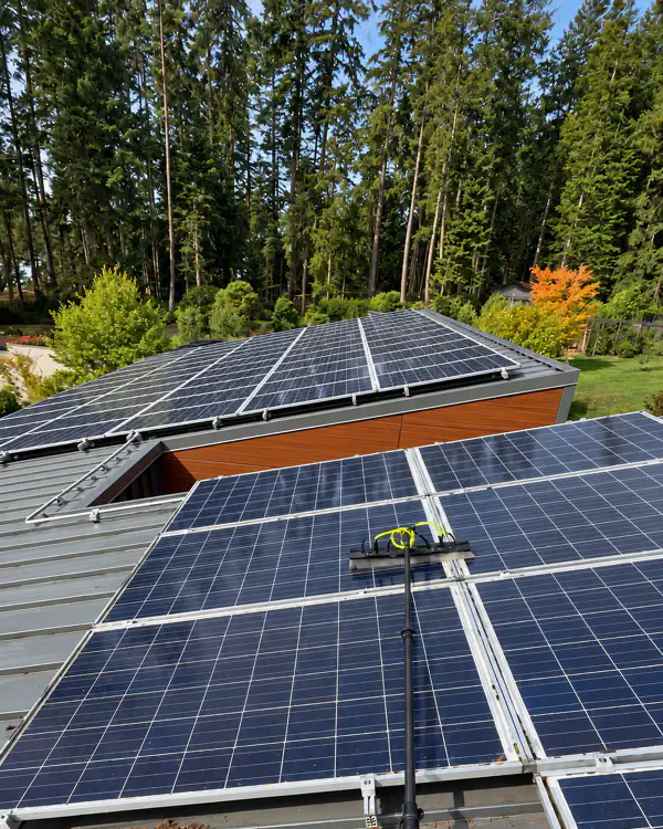 Solar panels on a roof, with a cleaning pole resting on them.